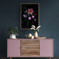 A framed dark botanical print of colourful Dahlias, Cosmos, Asters and Mallow on a black background, hung on a dark teal wall.