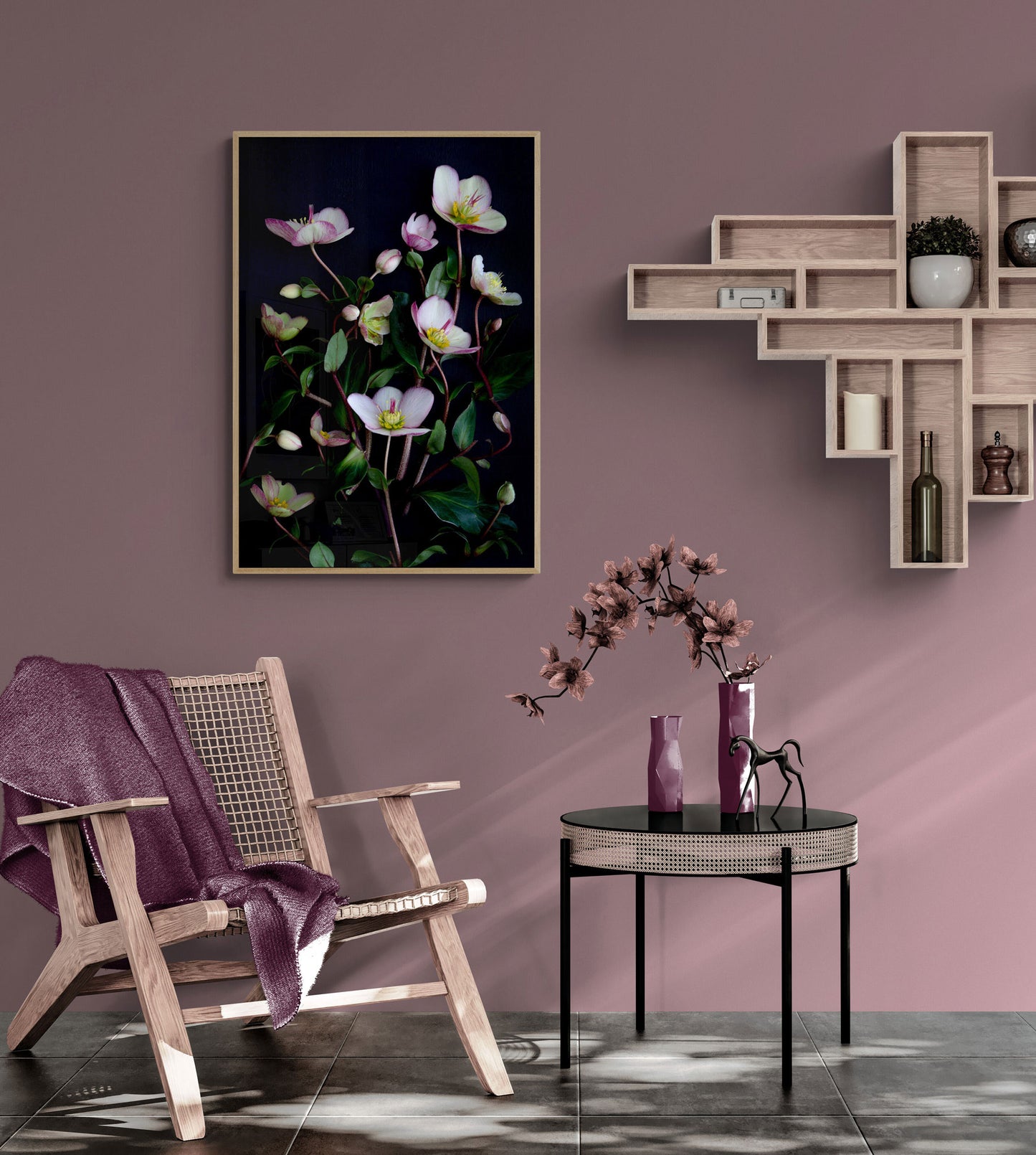 Dark botanical print ofpale pink Picotee hellebores photographed on a black background hung on a pink wall above a wooden chair and accessories.