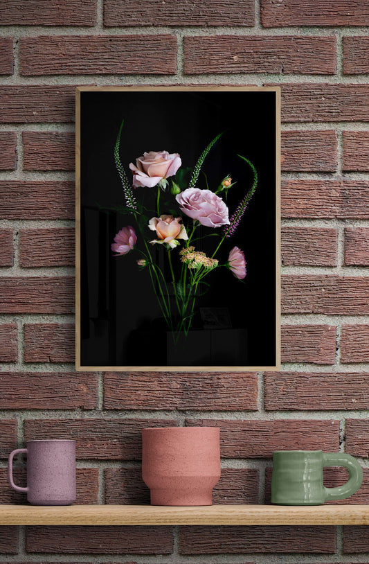 A posy of Koko Loco roses, Achillea, Cosmos and Veronica photographed on a black background and framed and hung on a brick wall.
