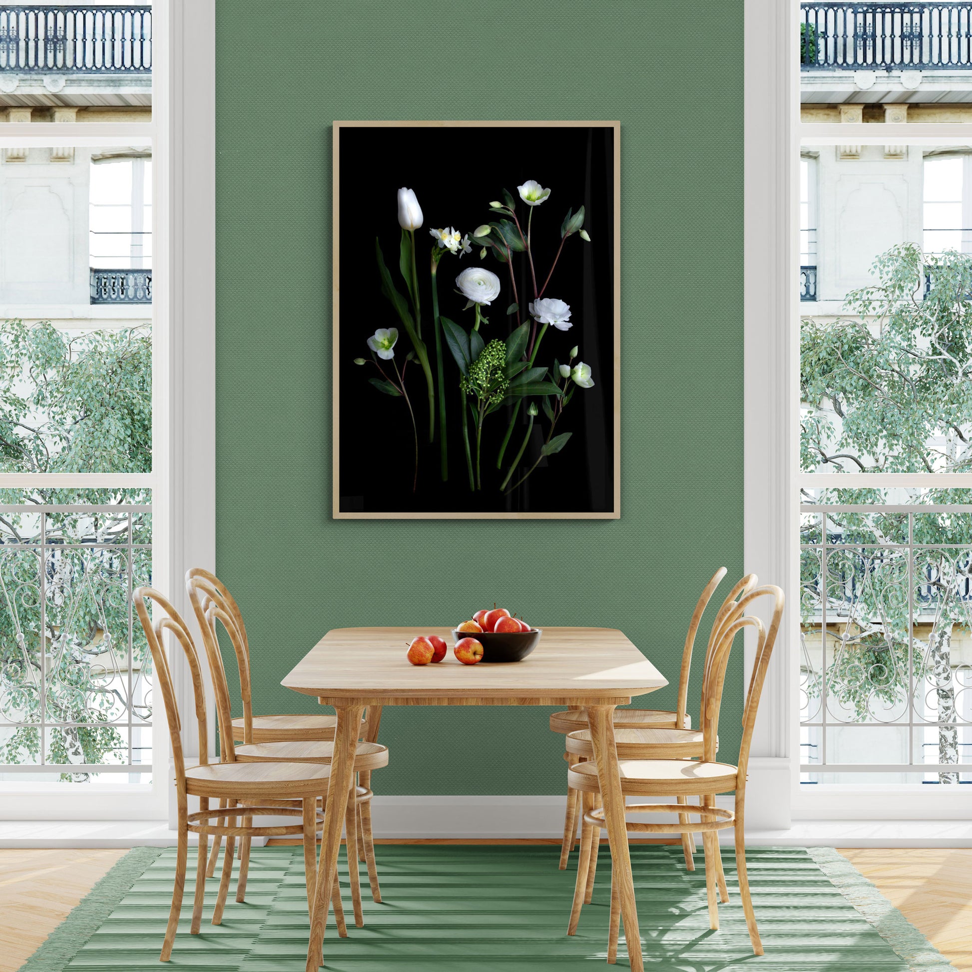 Framed dark botanical print of white Ranunculus , Narcissi, Hellebores and Skimmia photographed on a black background, hung on a green wall.
