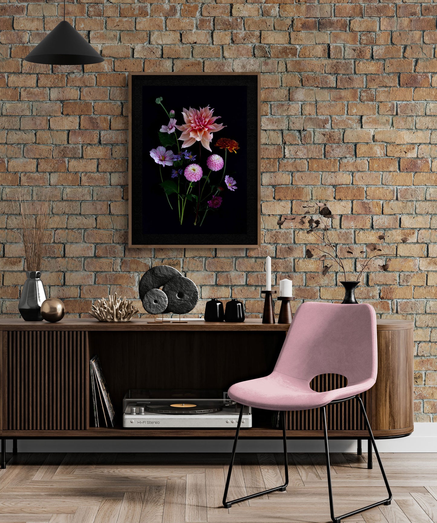 A framed dark botanical print of colourful Dahlias, Cosmos, Asters and Mallow on a black background, hung on a light brick wall.