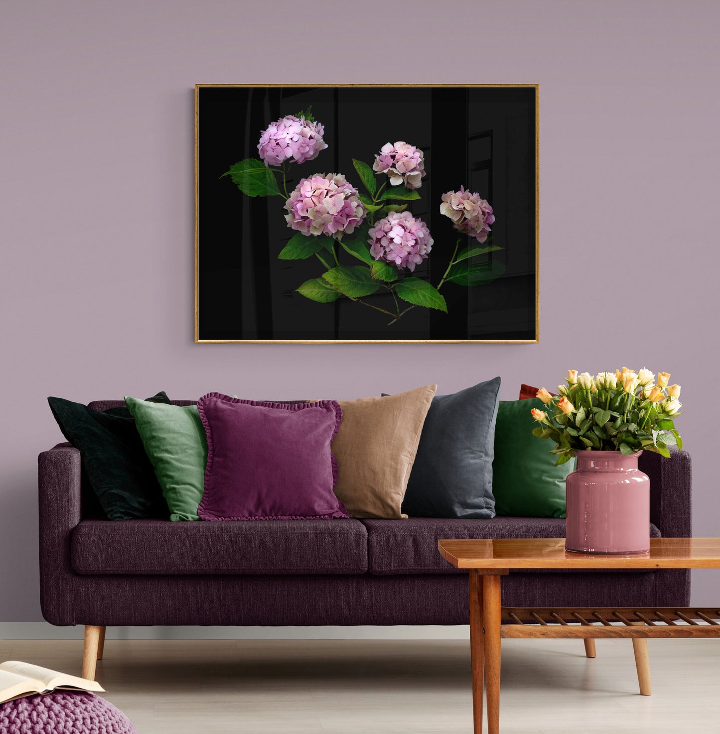 Dark botanical print of pink Hydrangeas on a black background, framed and hung on a lilac coloured wall above a sofa.
