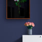 Dark botanical print, featuring a single, salmon -coloured Rose on a black background, frame, on a blue wall.