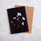 Botanical greeting card with pink Hellebores on a black background