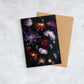 Botanical greeting card with Chrysanthums of varying colours  photographed on a black background.