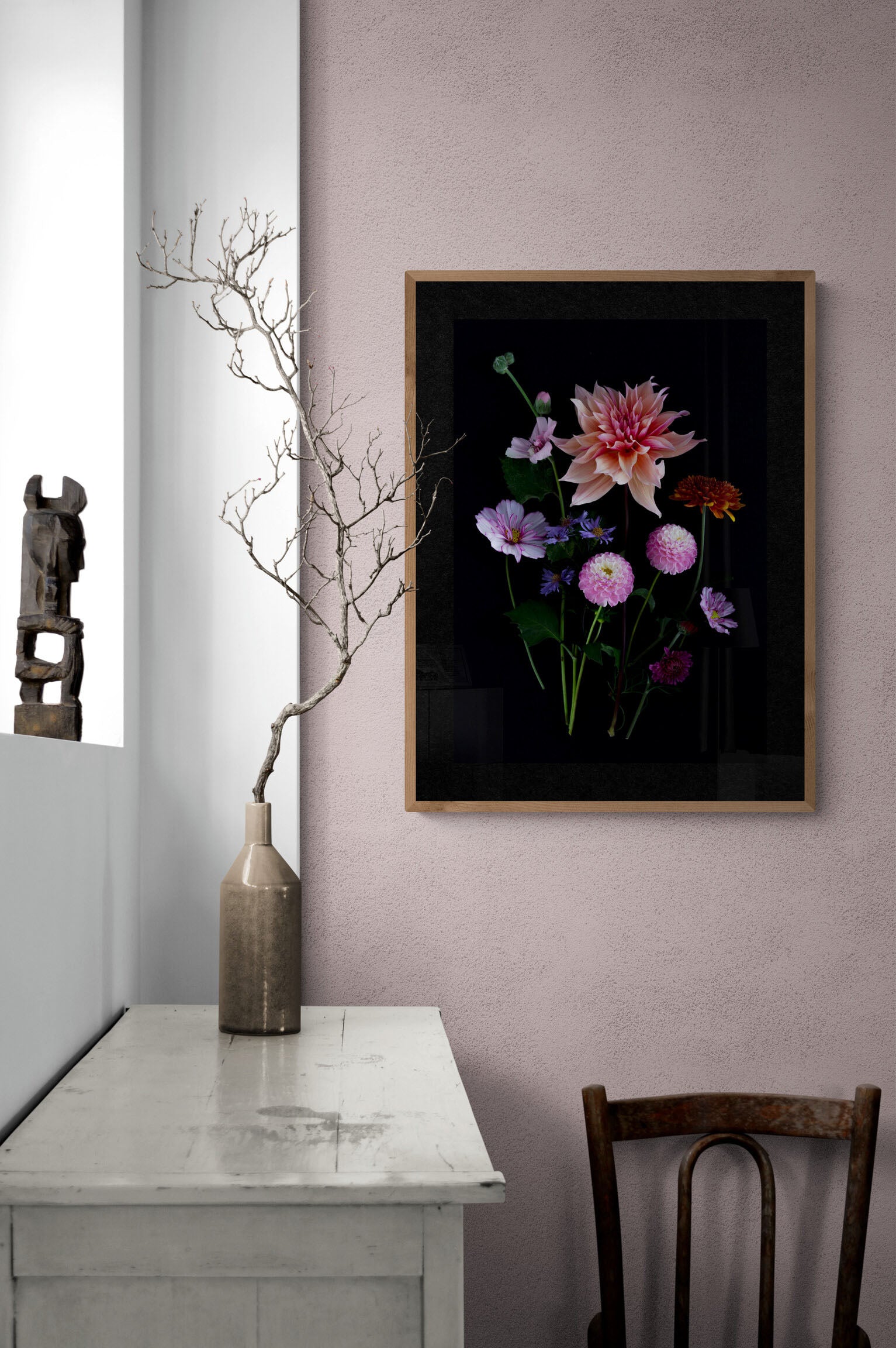 A framed dark botanical print of colourful Dahlias, Cosmos, Asters and Mallow on a black background, hung on a pale pink wall.